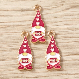Macro view of three cartoon gnome pendants with red hats and gold finish for DIY jewelry