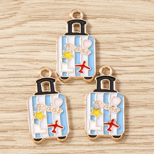 Détail de breloques valise bleues avec étoiles et avions pour bijoux DIY