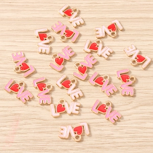 Macro shot of gold plated LOVE heart charms with pink enamel for DIY jewelry making