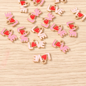 Macro shot of LOVE letter enamel heart pendants on a wooden table for DIY jewelry