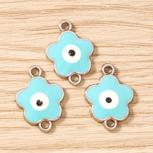 Tre connettori per gioielli malocchio a forma di fiore blu su fondo legno