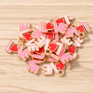 Close-up of enamel LOVE heart charms for DIY jewelry making in pink and red colors