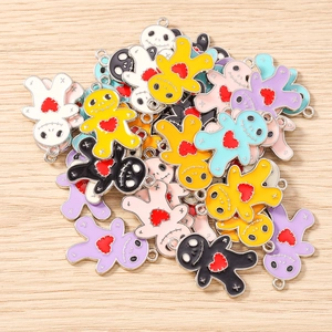 Close-up of colorful enamel voodoo doll pendants with red heart detail for DIY jewelry
