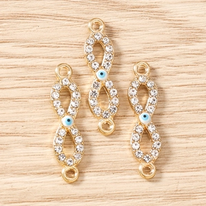 Makroaufnahme von Gold-Unendlich-Anhängern mit Kristallen und blauem Evil Eye