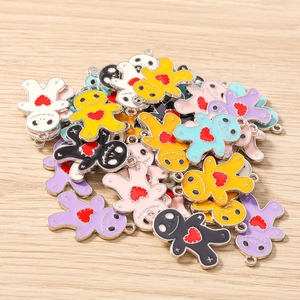Colorful Voodoo Doll enamel pendants with heart detail on a natural wood surface