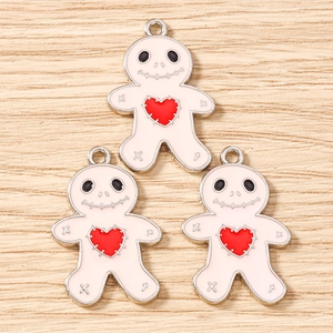 Close-up of three gingerbread man enamel charms with red hearts on a wooden surface