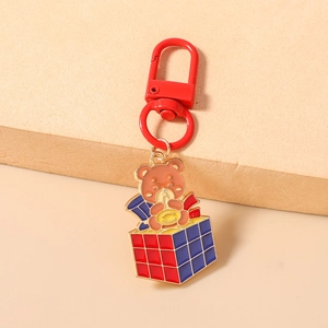 Dettaglio dell'orso che suona il sassofono con mini cubo magico su portachiavi rosso