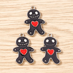 Detail of three black skeleton gingerbread man charms with red hearts on wood