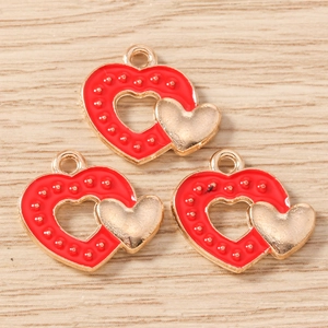 Vue macro de trois pendentifs coeur en émail rouge avec bordure dorée sur bois