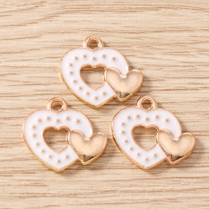 Détail de trois pendentifs double cœur en émail blanc avec relief doré à pois