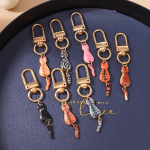 Close-up of eight multicolored enamel cat keychains with gold-tone metal D-rings