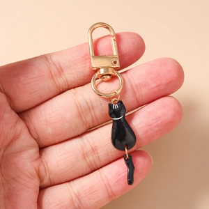Close-up of cute black enamel cat keychain with golden clasp and movable tail detail