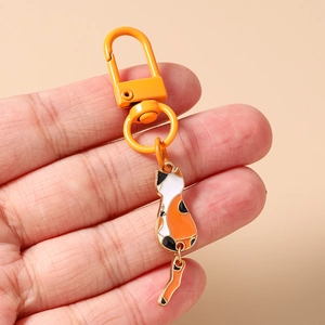 Detailed view of calico cat keychain with orange lobster clasp and movable tail part