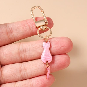 Detail of pink enamel cat keychain with movable tail and gold lobster clasp