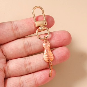 Detailed close-up of a golden metal D-buckle with an orange tabby cat enamel keychain charm