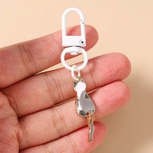Close-up of cute cartoon cat keychain with swinging tail and golden metal details