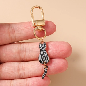 Detail of hand-held gold cat keychain with black and white zebra stripes for handbags