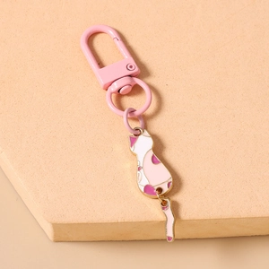Close-up of pink cat keychain with movable tail and golden edges on peach background