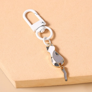 Detail of cute cartoon cat keychain featuring a white metal clasp and movable metal tail
