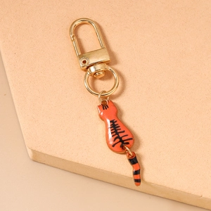 Close-up of cute orange cat keychain with a movable tail on a beige stone display
