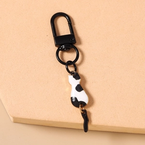 Detail of cute black and white cat charm with swinging tail and black metal clasp