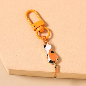 Detail of cute calico cat keychain with orange lobster clasp on beige textured background