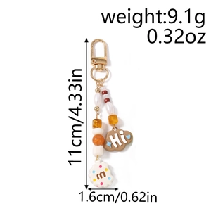 Detail showing beaded keychain with 'Hi' cloud and 'm' biscuit charms and gold clasp