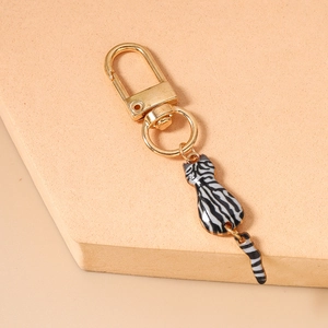 Detailed view of gold cat keychain with black and white striped enamel and movable tail