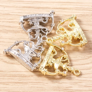 Detailed macro view of gold and silver crown pendants with rhinestones on wood