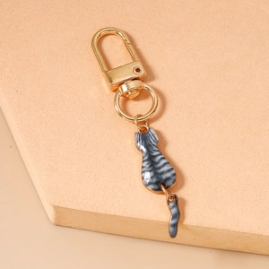Macro detail of a golden cat keychain with grey tabby enamel and movable tail structure