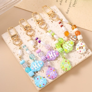 Colorful beaded keychains with cloud charms and gold clasps on a white marble board