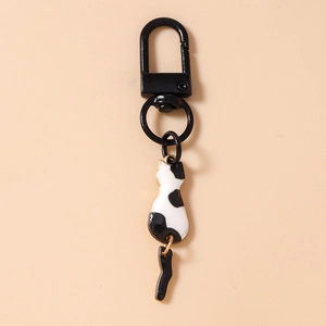 Close-up of cute black and white cow print cat keychain with black spring clasp and metal ring
