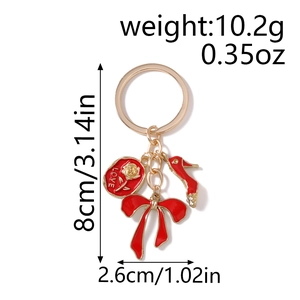 Detailed view of gold keychain featuring red enamel rose, shoe and bow charms