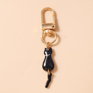 Detail of cute black enamel cat keychain with golden D-ring clasp and movable tail