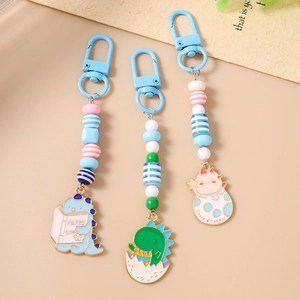 Detail view of colorful beaded dinosaur keychains with enamel charms and metal snap hooks