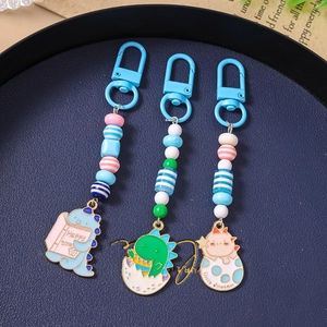 Cute cartoon dinosaur keychains with colorful beads and charms on a navy tray
