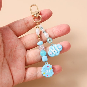 Detail of beaded keychain with blue cloud, biscuit charms and gold metal clasp