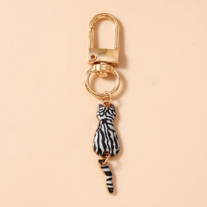 Detail of cute cat keychain with gold frame and zebra pattern on a beige background