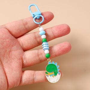 Close-up of cute cartoon dinosaur keychain with colorful beads and blue lobster clasp