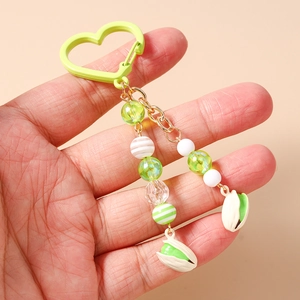 Dettaglio del portachiavi al pistacchio con chiusura a cuore e nappe verdi in mano