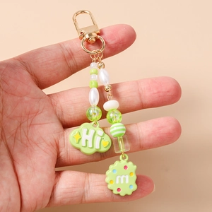 Detail view of a green beaded keychain with a cloud pendant and letter cookie charm