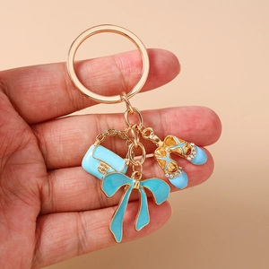 Detail of blue enamel handbag, bow, and rhinestone ballet shoes charms on gold keychain