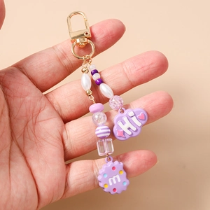 Detail of purple beaded keychain featuring a Hi cloud charm and alphabet biscuit pendant