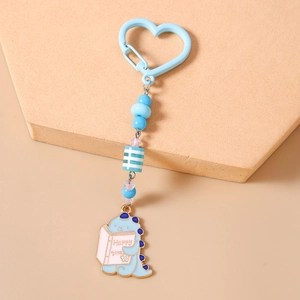 Détail d'un porte-clés dinosaure avec perles, crochet coeur bleu et breloque émail