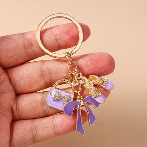 Detailed close-up of purple rhinestones and enamel handbag charms on gold keychain