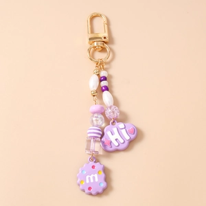 Detail of purple beaded keychain with cloud Hi pendant and cookie m charm on gold clasp