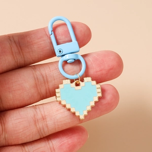 Close-up of blue pixel heart keychain held by hand featuring a metal lobster clasp