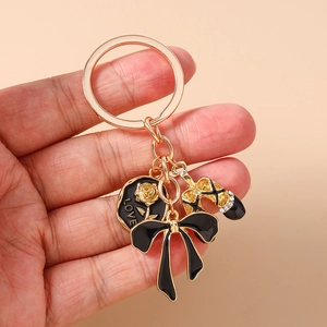 Detail view of gold keychain with black bow, rhinestone high heel, and love rose pendant