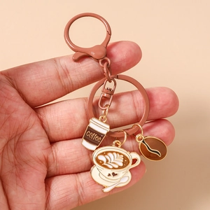 Detail of enamel coffee bean keychain with latte art cup and brown metal ring pendant