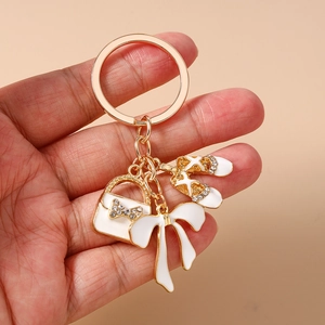 Detailed view of gold keychain featuring rhinestone handbag, ballet shoes, and white bow charm